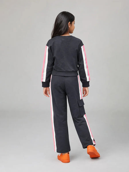 Person wearing a black tracksuit with pink stripes on a gray background