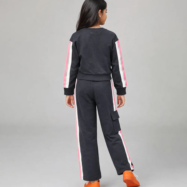 Person wearing a black tracksuit with pink stripes on a gray background