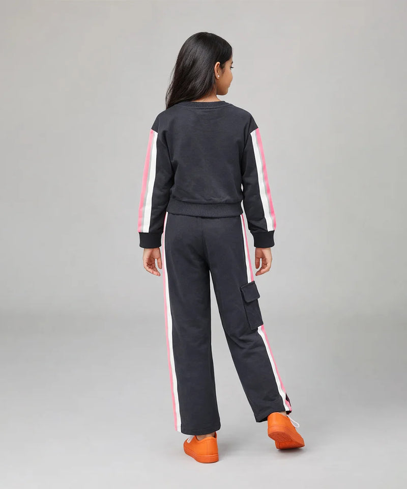 Person wearing a black tracksuit with pink stripes on a gray background