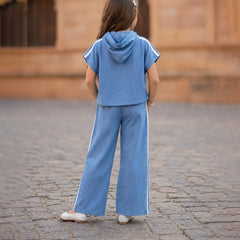 Child wearing a blue outfit standing on a cobblestone street with a blurred background