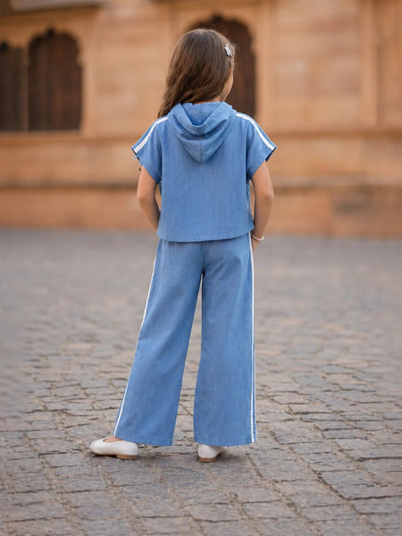 Child wearing a blue outfit standing on a cobblestone street with a blurred background