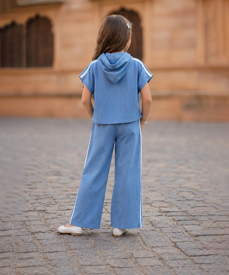 Child wearing a blue outfit standing on a cobblestone street with a blurred background
