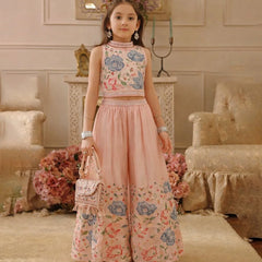 Young girl in a floral outfit standing in an elegant room with floral decorations.