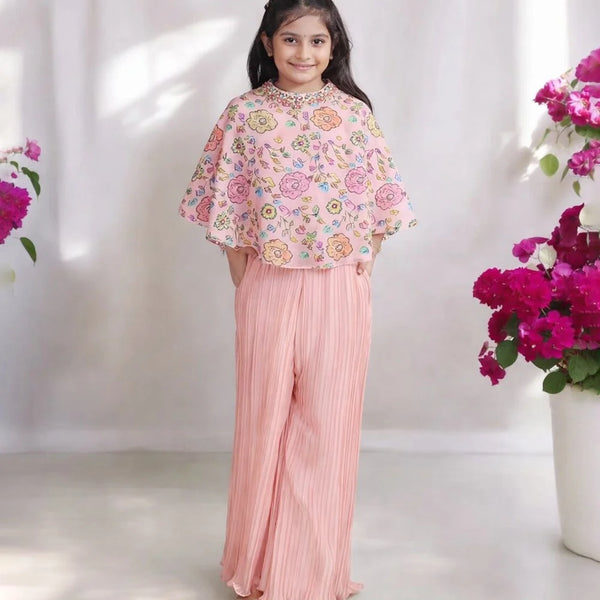 Young girl in a floral top and pink pants standing between two flower arrangements on a white background