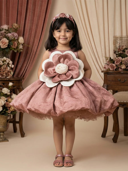 Young girl in a pink floral dress standing in a decorated room with flowers and furniture.