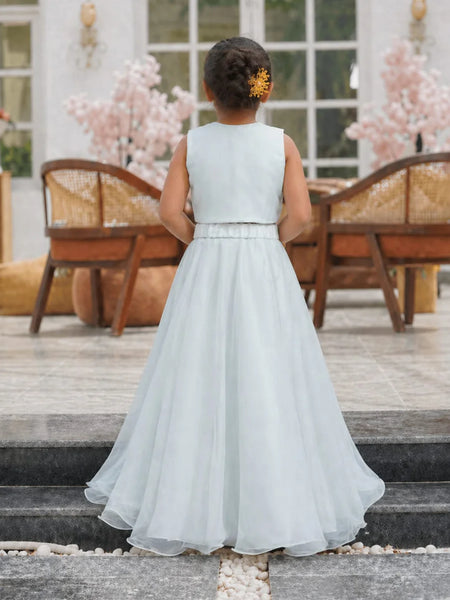 Young girl in a light blue dress standing on steps with a decorative background