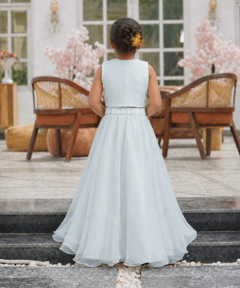 Young girl in a light blue dress standing on steps with a decorative background
