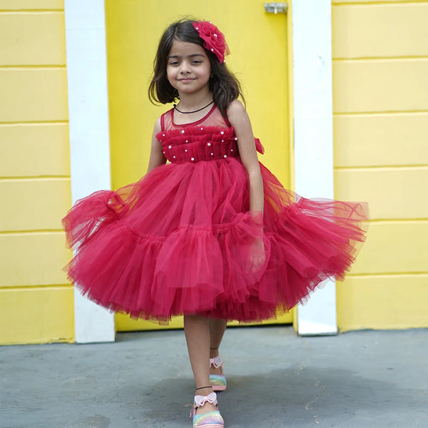 It's a fancy red frock that features a matching hairpin curated from net fabric and pearl detailing on the dress. Moreover, it comes with a fabric belt to be tied at the back.