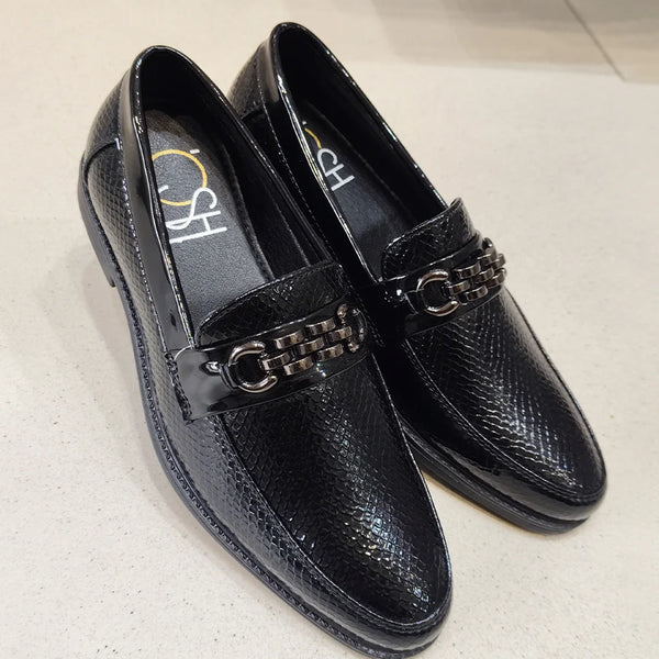 Black loafers with chain detail on a light gray background