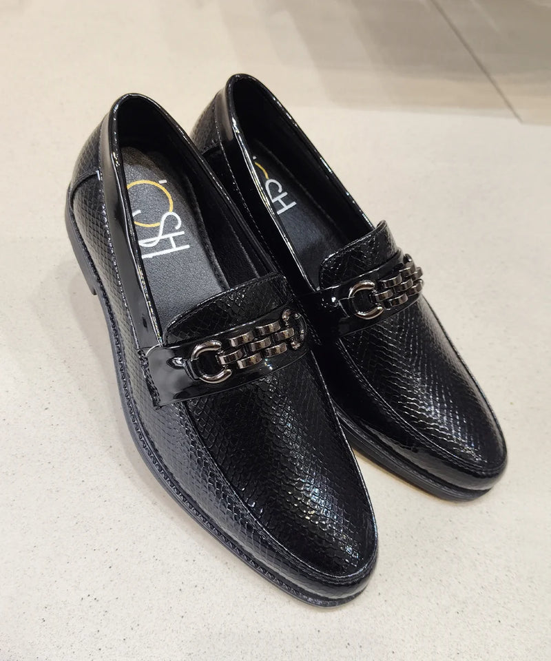 Black loafers with chain detail on a light gray background