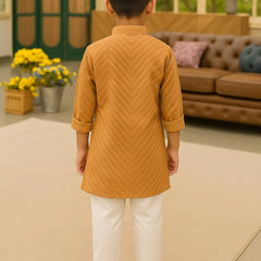 Child wearing a mustard yellow kurta with white pants in an indoor setting.