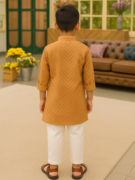 Child wearing a mustard yellow kurta with white pants in an indoor setting.