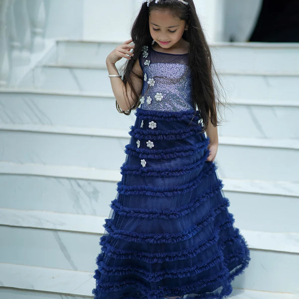 Young girl in a blue formal gown standing on steps.