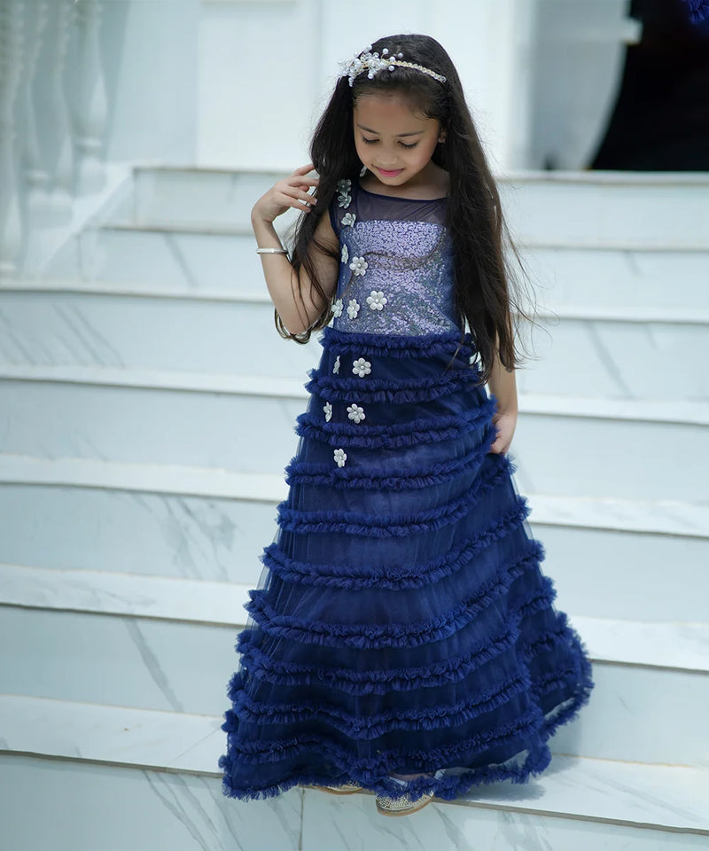 Young girl in a blue formal gown standing on steps.