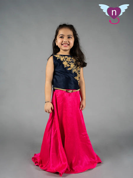 Young girl wearing a black top with gold embroidery and a pink skirt on a gray background