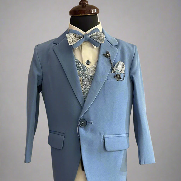 This coat suit for boys consists of a coat, matching pants, a self-printed waistcoat, and a white Colored shirt. It features a matching printed bow, a broach and a printed pocket square.