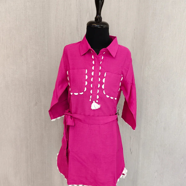 Pink outfit with white embroidery on a mannequin against a plain background