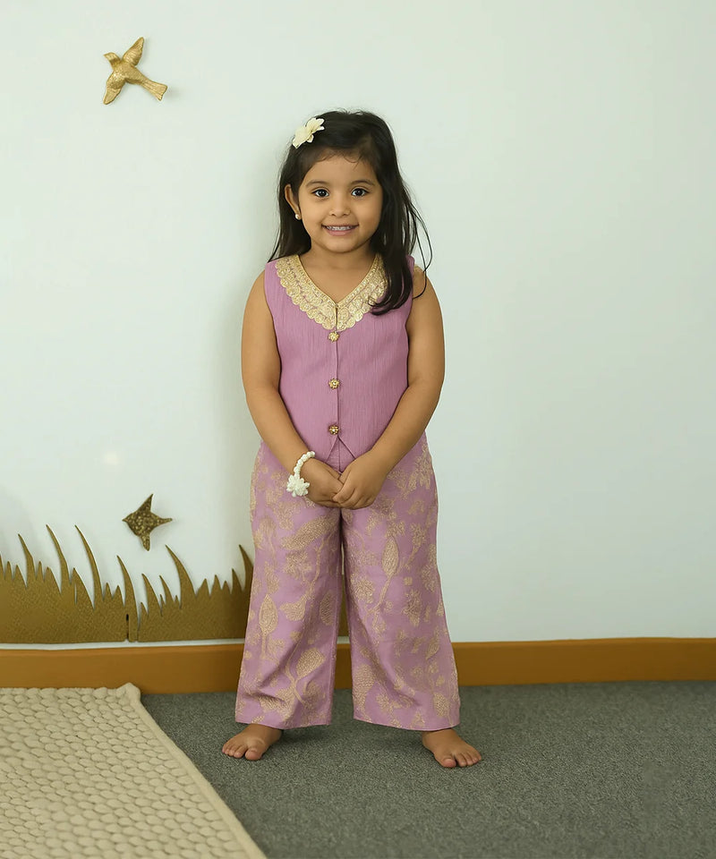 Young girl in a pink outfit standing in a room with a white wall and decorative elements.