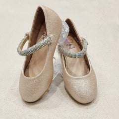 Pair of glittery gold shoes with decorative straps on a light background