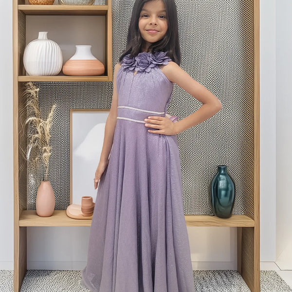 Young girl in a purple dress standing in front of a wooden shelf with decorative items.