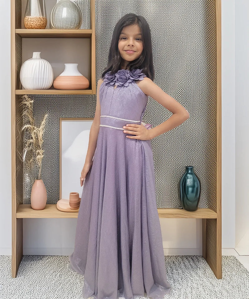 Young girl in a purple dress standing in front of a wooden shelf with decorative items.