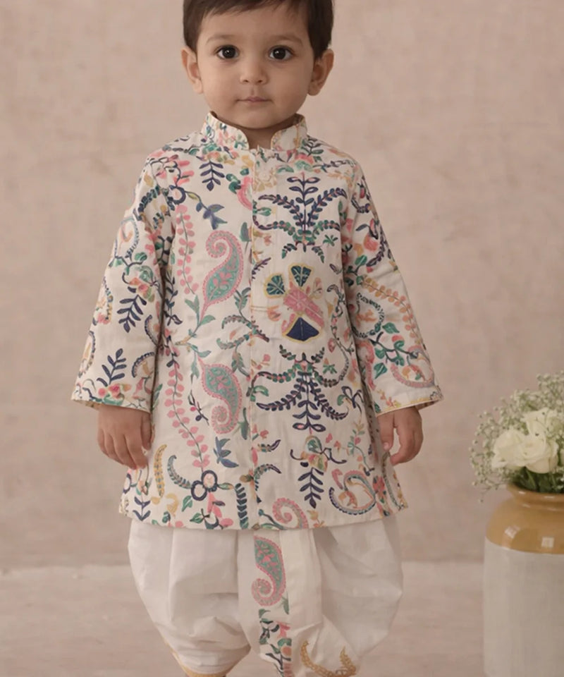 Child wearing a traditional embroidered outfit with a neutral background