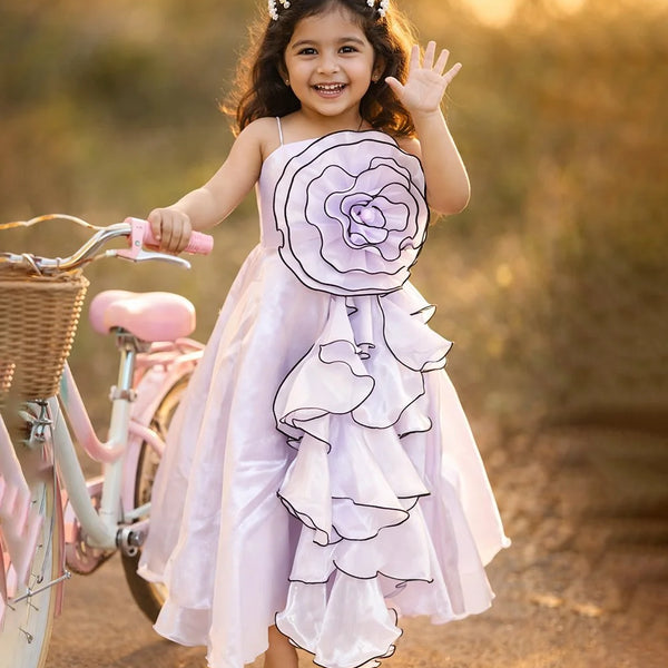 Young girl in a floral dress standing next to a bicycle with a blurred natural background