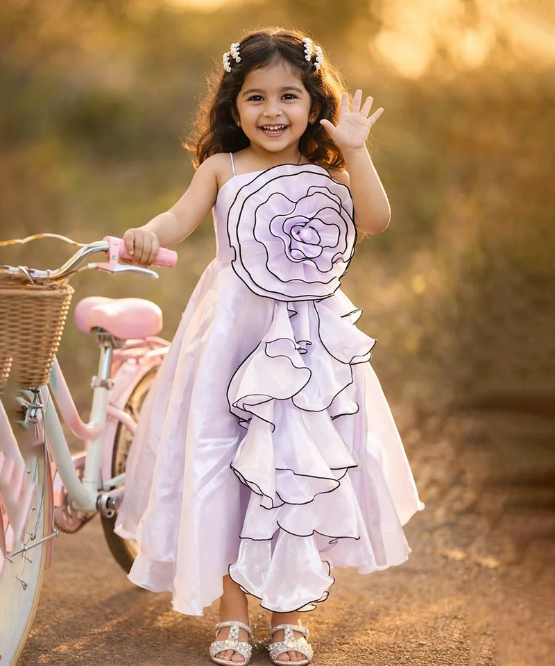 Young girl in a floral dress standing next to a bicycle with a blurred natural background
