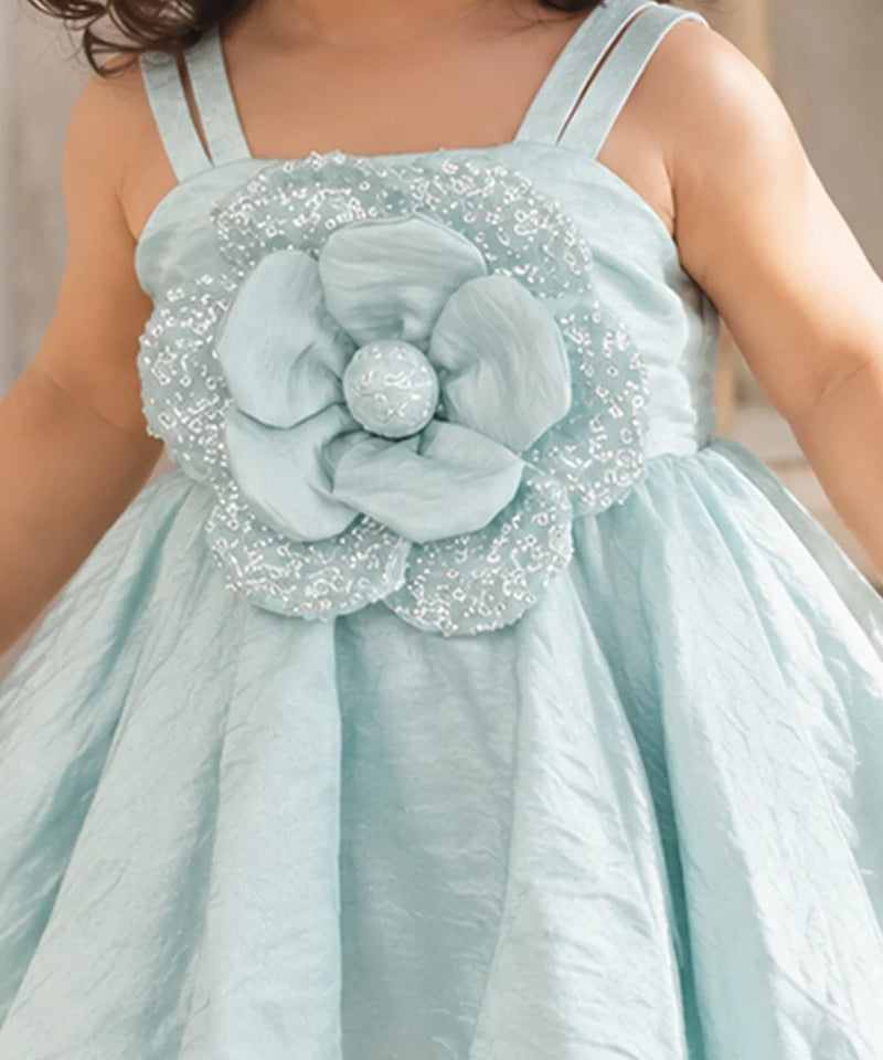 Close-up of large layered 3D flower appliqué on the waist of pastel blue baby girl frock