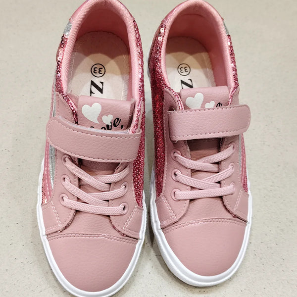 Pair of pink children's sneakers with heart designs on a beige background