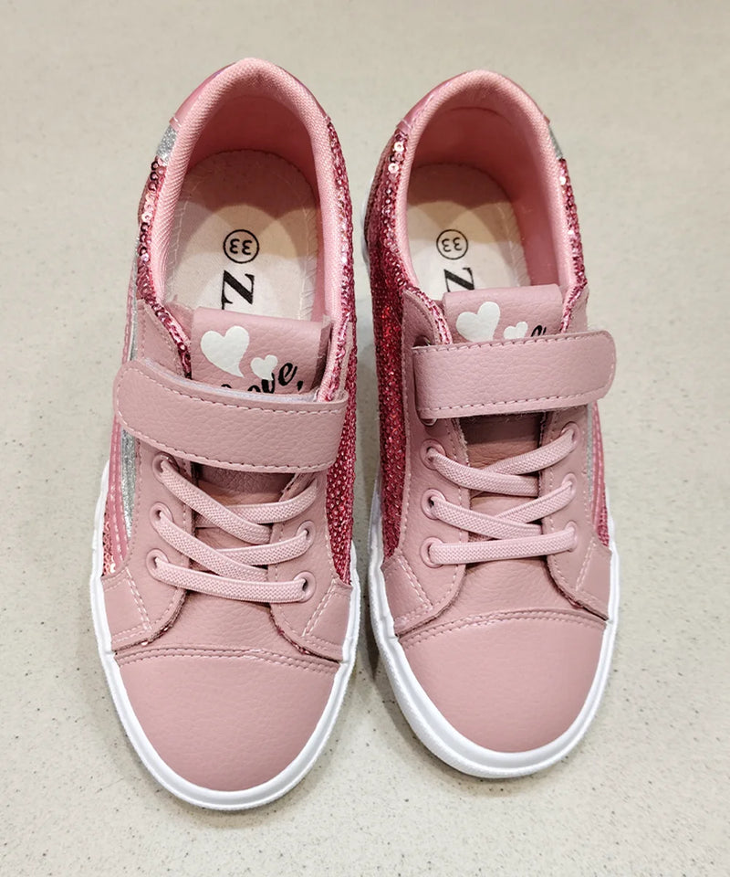 Pair of pink children's sneakers with heart designs on a beige background