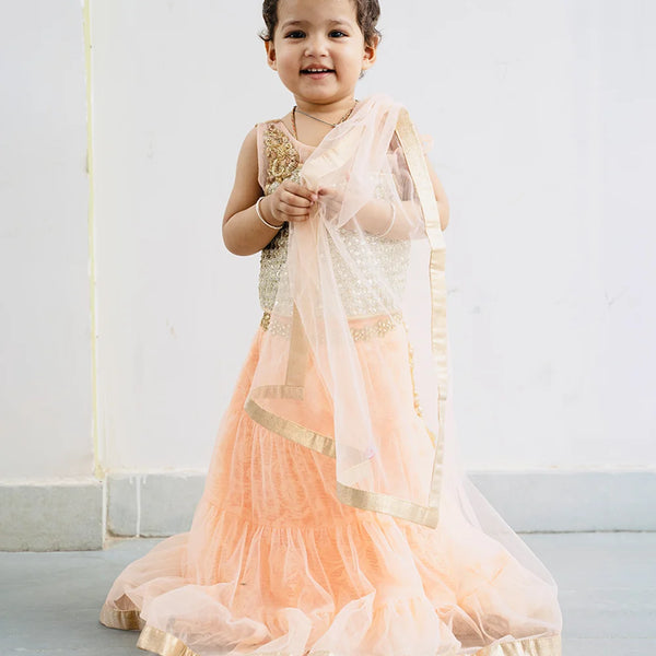 This traditional lehenga for kids consist of a choli, a tiered Lehenga and a dupatta for your kids with a back hook closure. It features embellished shoulder and choli. Moreover, skirt has a lace work on the waist and tassel detailing on it.