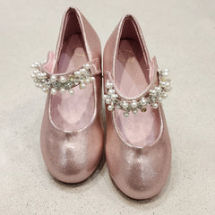 Pair of pink glittery shoes with decorative straps on a light background