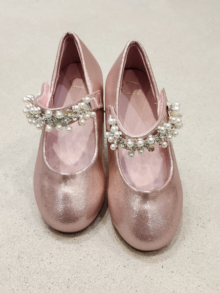 Pair of pink glittery shoes with decorative straps on a light background