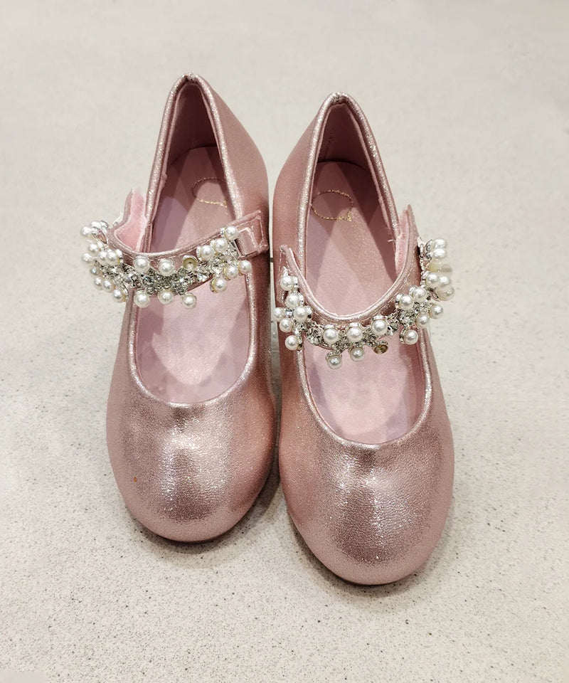 Pair of pink glittery shoes with decorative straps on a light background