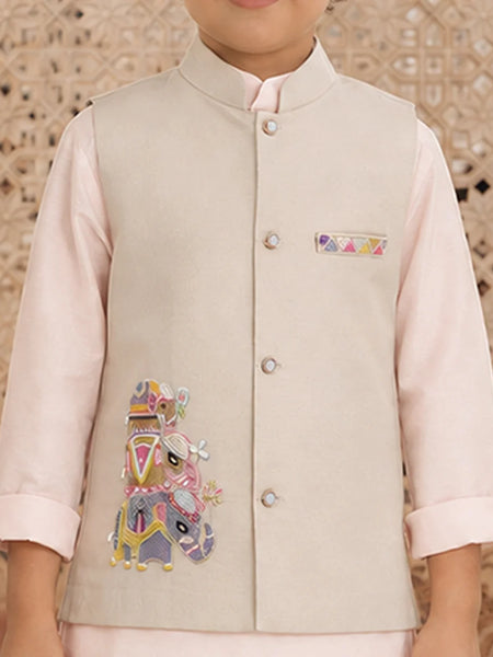 A child wearing a light beige embroidered waistcoat over a pale pink kurta, with a decorative geometric patterned background.