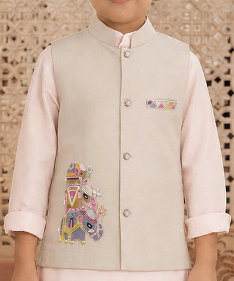 A child wearing a light beige embroidered waistcoat over a pale pink kurta, with a decorative geometric patterned background.