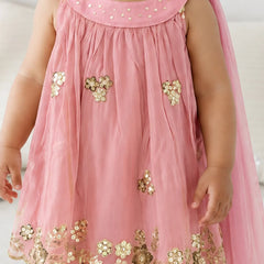A pink sleeveless dress with gold floral embroidery and sequins, worn by a child. The dress features a scalloped hem with gold floral applique and a matching pink dupatta draped over the shoulders.