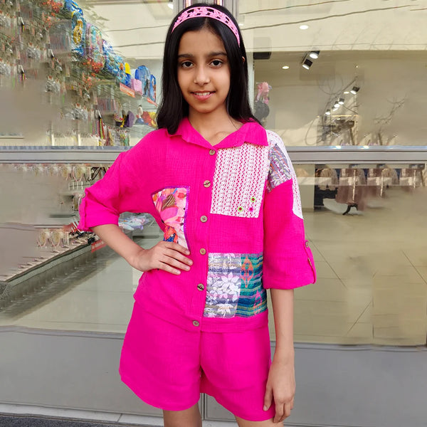 Young girl wearing a bright pink outfit with a colorful patterned shirt in an indoor setting.