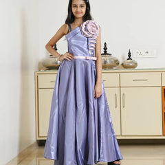 Girl in a purple gown with a floral detail standing in a room.