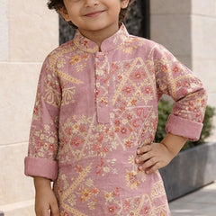 Child wearing a pink traditional outfit with floral patterns standing outdoors.