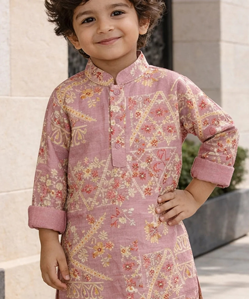 Child wearing a pink traditional outfit with floral patterns standing outdoors.