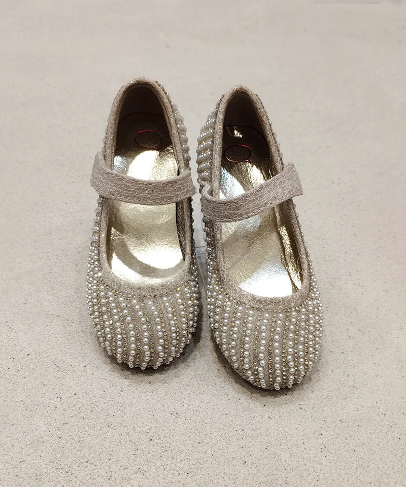 Pair of pearl-beaded shoes on a beige background