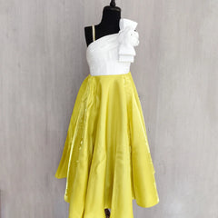 White top and yellow skirt on a mannequin against a gray background