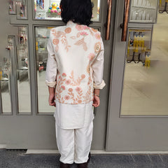 Person wearing a floral embroidered outfit standing in front of a kidswear store