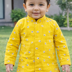Child wearing a yellow traditional outfit with floral patterns outdoors.
