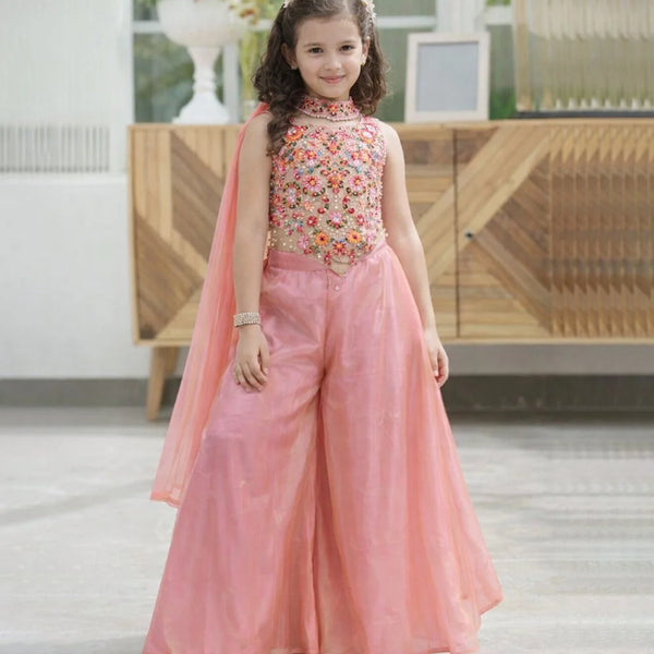 Young girl in a pink traditional outfit with floral top in a bright room.