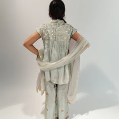 Girl wearing a light green traditional outfit with a floral pattern on a white background