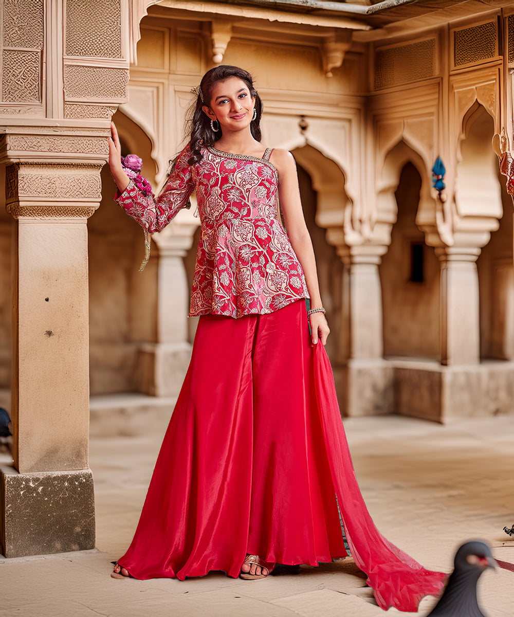 Woman in a red and pink traditional outfit standing in an architectural setting.