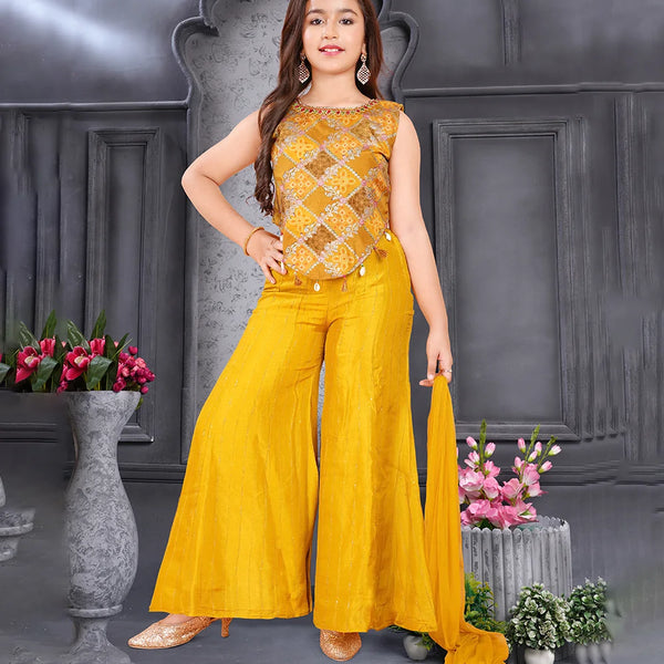 Woman in a yellow outfit standing in front of a decorative background with flowers.